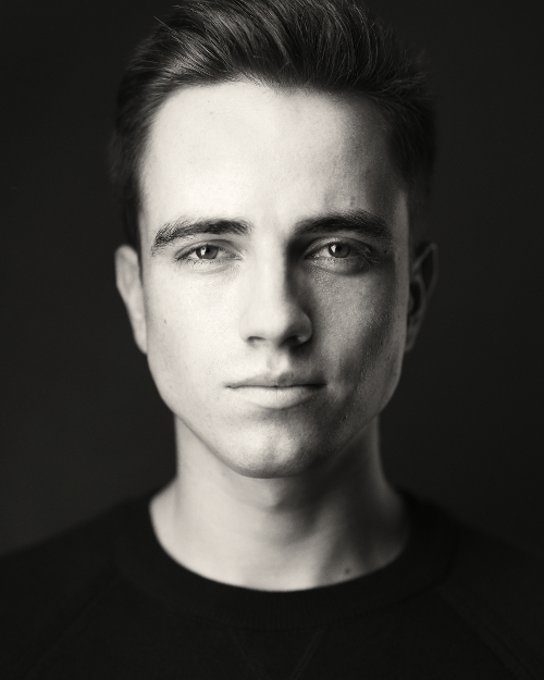 Portrait photo of white male with black background and clothing Portrait photo of white male with black background and clothing